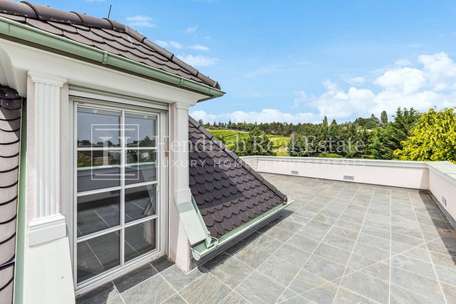 Sonnige Dachterrasse mit Fliesenboden und weitem Blick über die umliegende Landschaft.