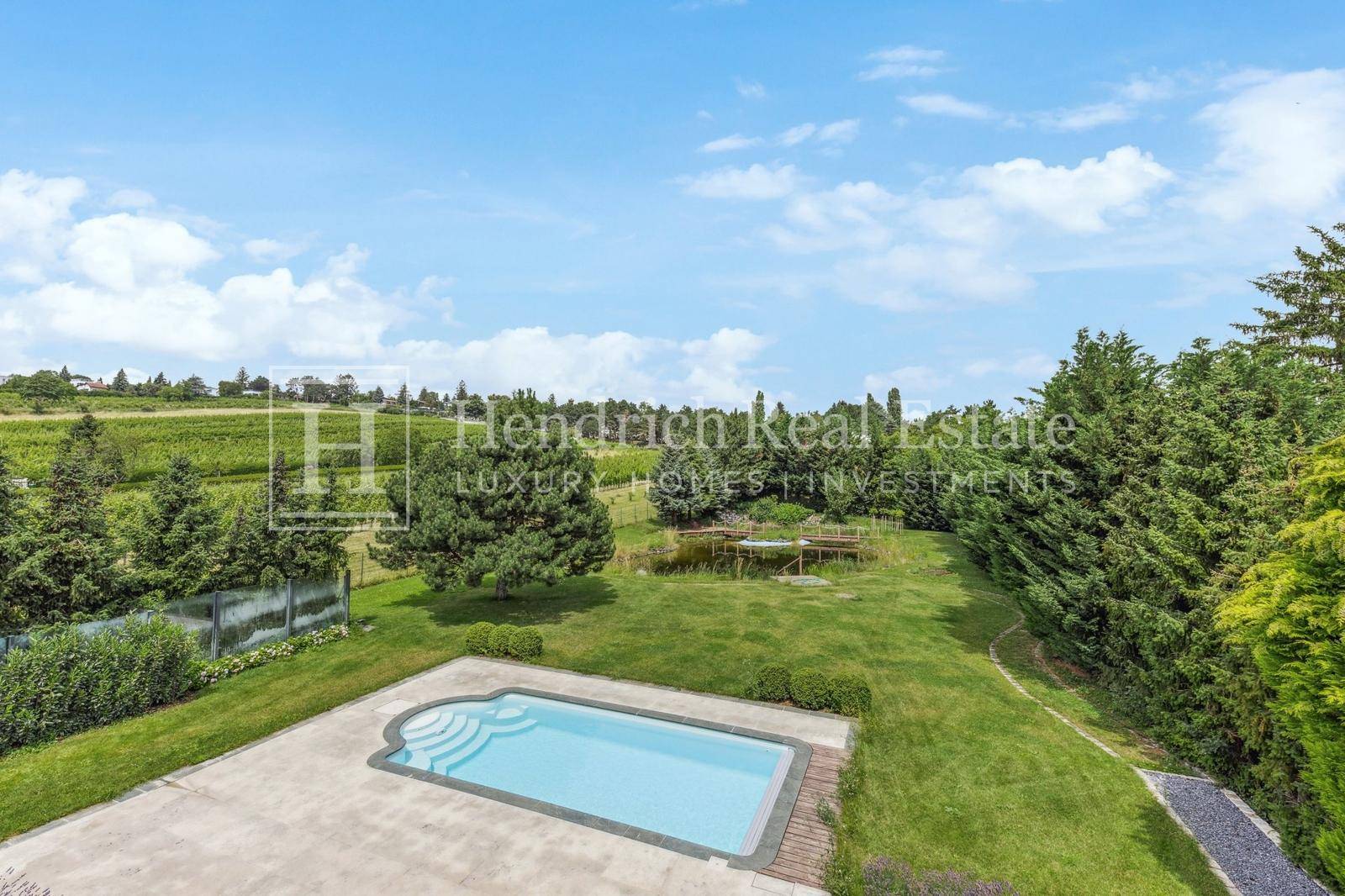 Weitläufiger Garten mit Pool, großer Rasenfläche und Blick auf die umliegenden Weinberge.
