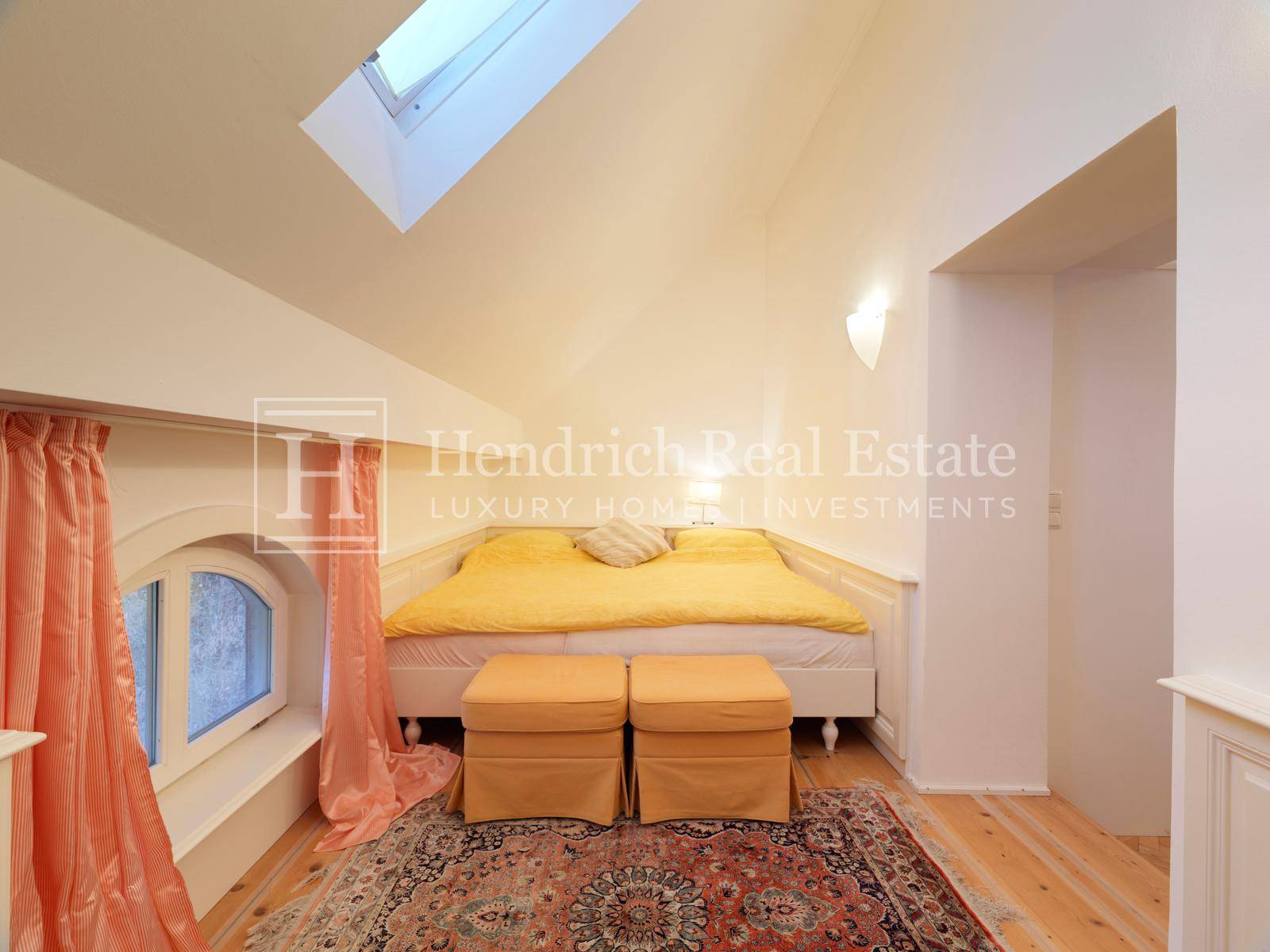 Charmantes Dachschlafzimmer mit schrägen Decken, Dachfenster und gemütlichem Bett.