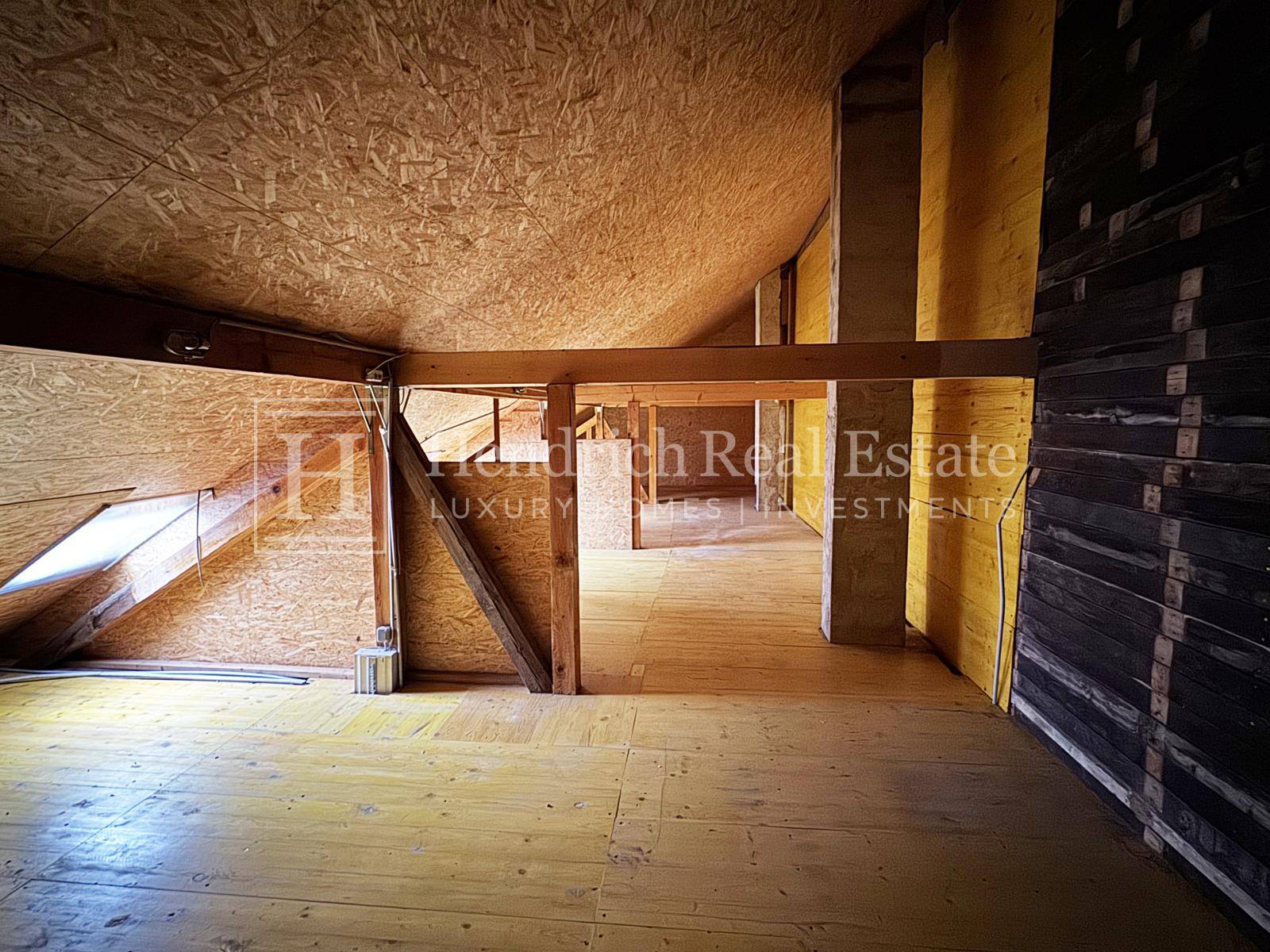 Unausgebauter Dachboden mit Holzkonstruktion und Dachfenster, bietet Ausbaupotenzial.