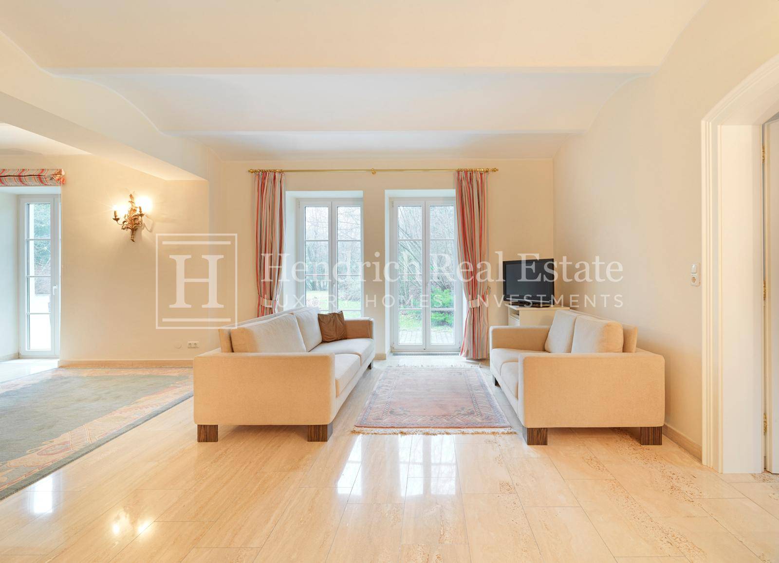 Helles Wohnzimmer mit hellem Fliesenboden, bequemen Sofas und Zugang zum Außenbereich.
