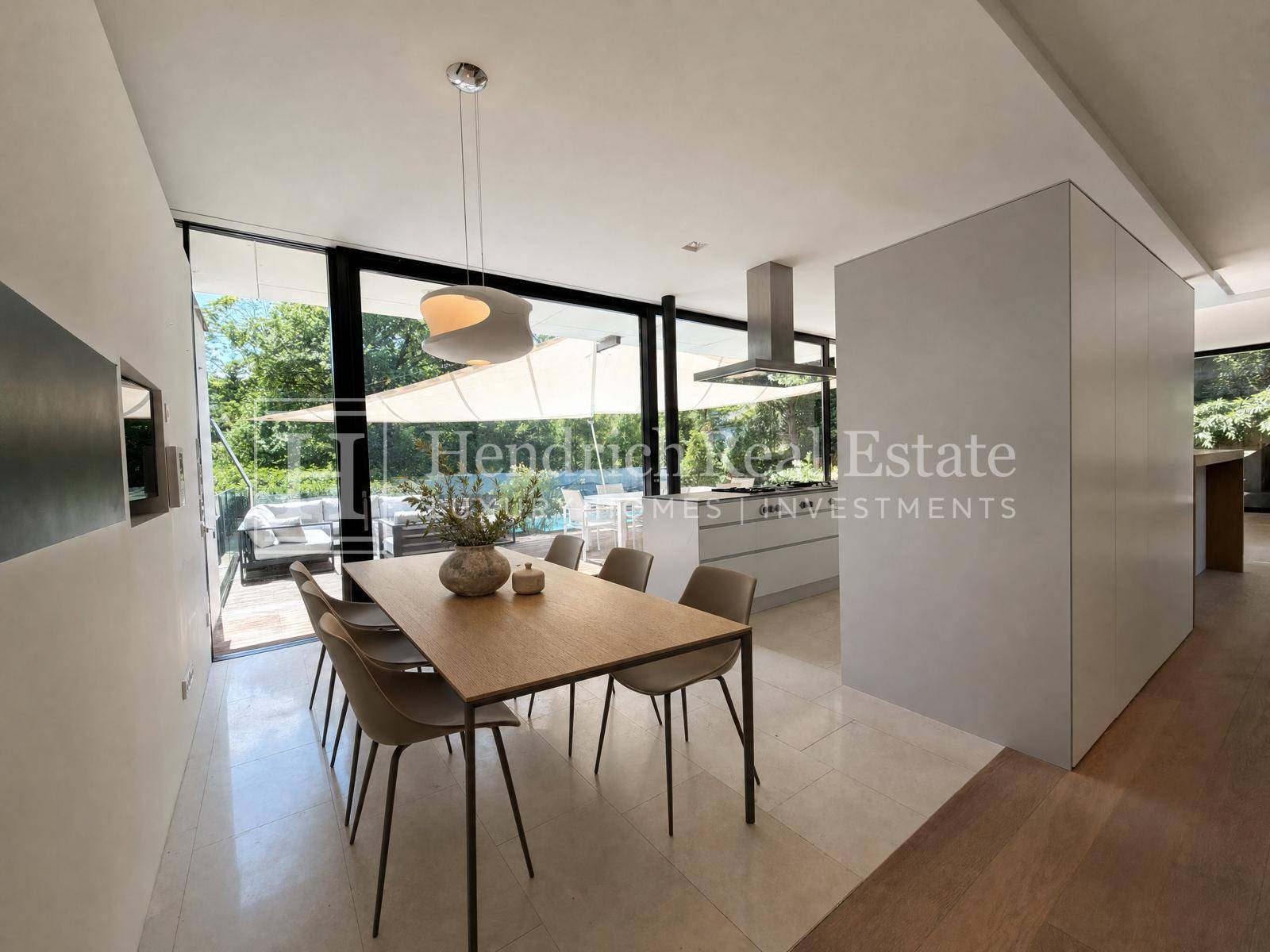Eleganter Essbereich mit Holztisch und Stühlen, angrenzend an eine moderne Küche mit großen Fenstern.