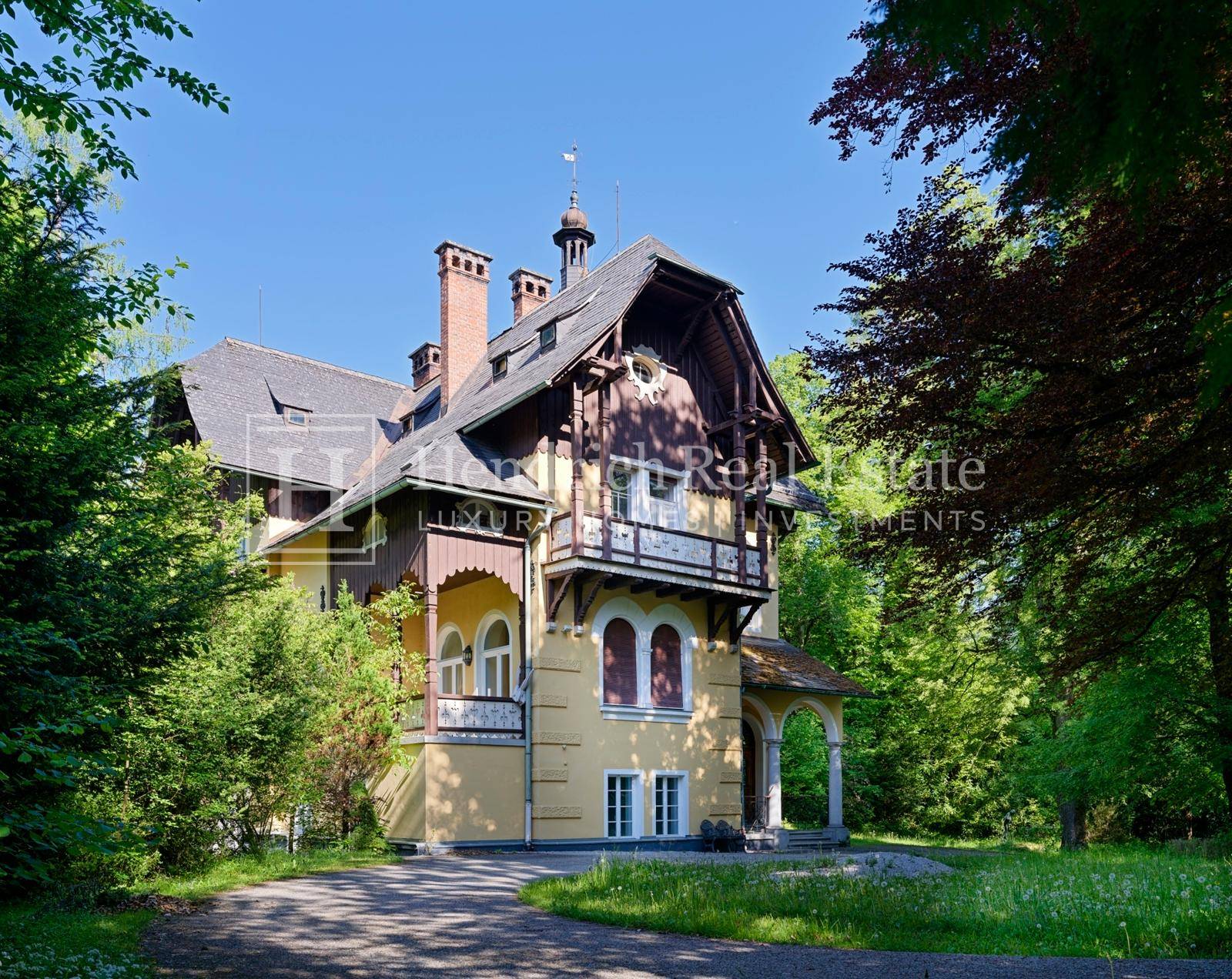 Elegante Villa mit traditioneller Architektur und weitläufigem Grundstück, eingebettet in eine grüne Landschaft.