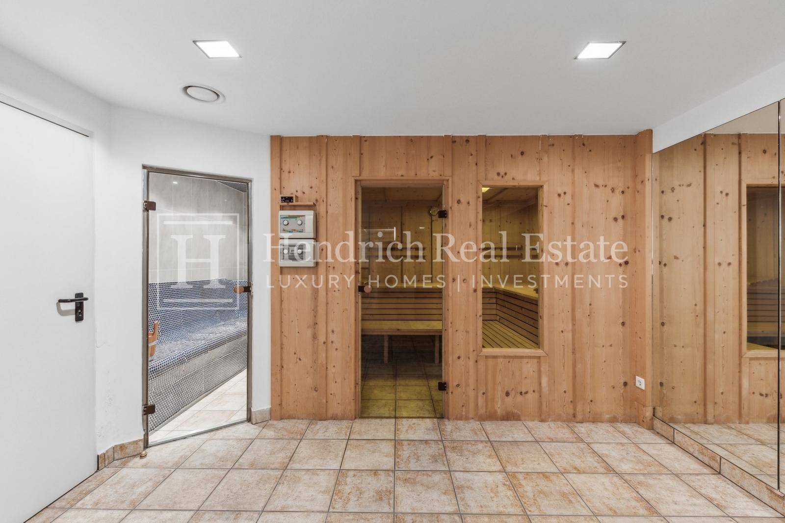 Moderner Wellnessbereich mit holzverkleideter Sauna und Zugang zu einem Dampfbad oder Pool.