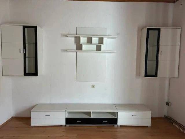 Wohnzimmer mit modernen weißen Wandregalen und einem passenden TV-Möbel auf Holzboden.