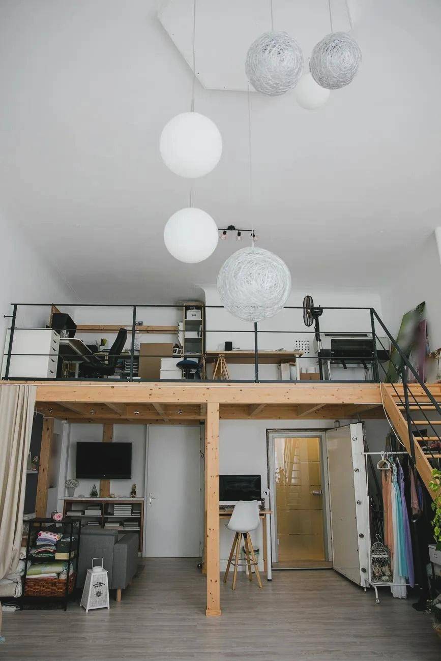 Heller Wohnbereich mit hoher Decke, Holz-Loft-Struktur und modernen Hängelampen, vielseitig nutzbar.