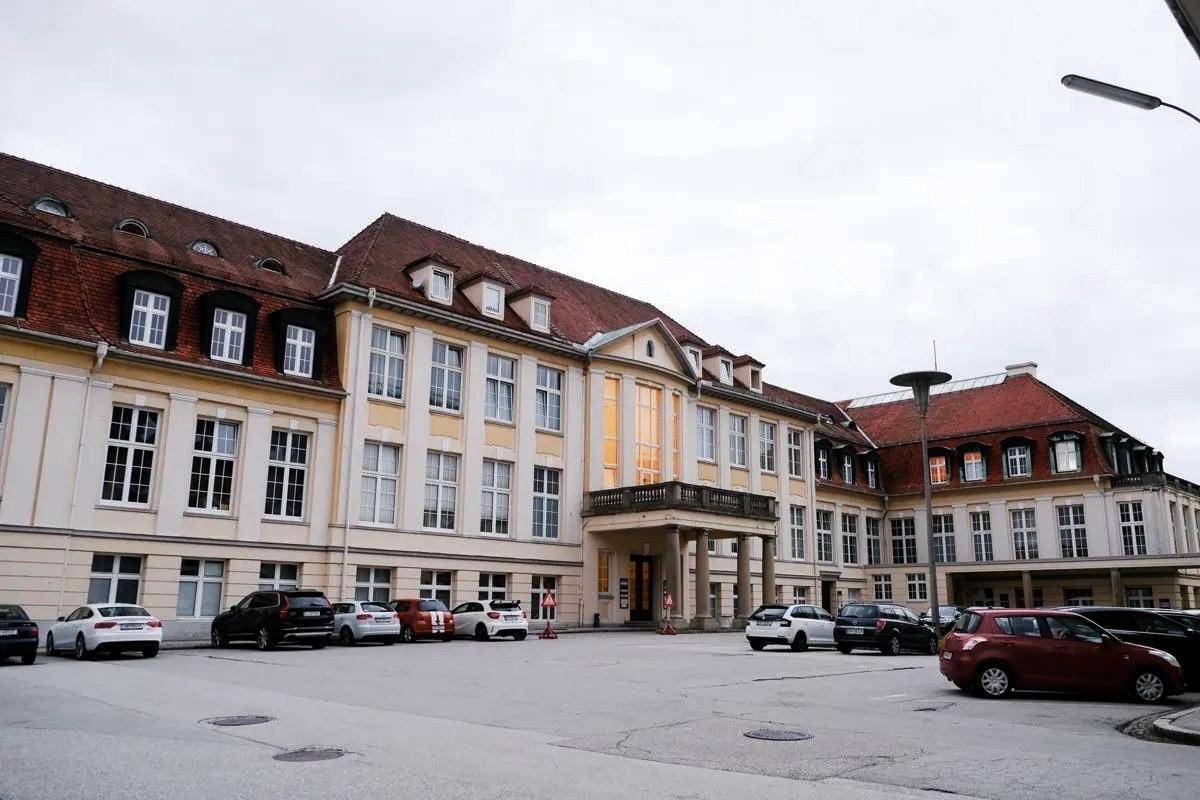 Großes, historisches Gebäude mit vielen Fenstern, einem Vorplatz und geparkten Autos.