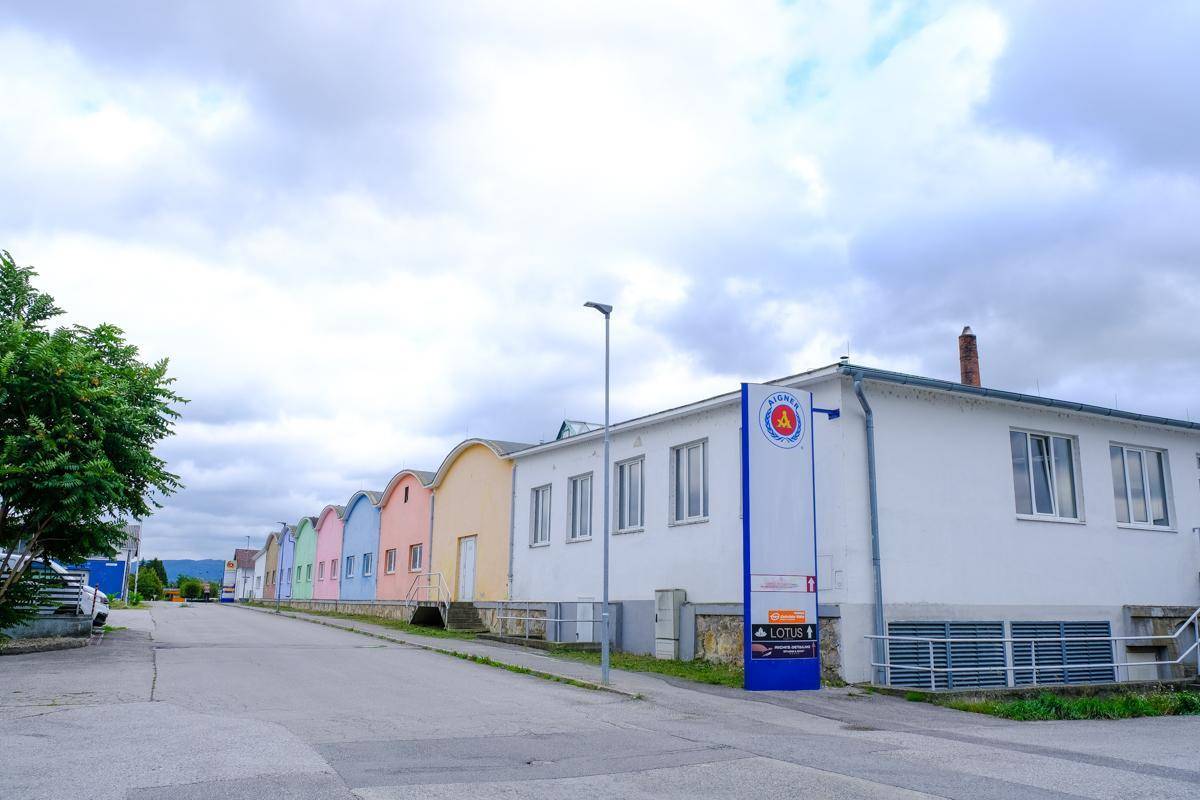 Straßenansicht mit einer Reihe bunter Gebäude und einem weißen Hauptgebäude mit Werbeschild.
