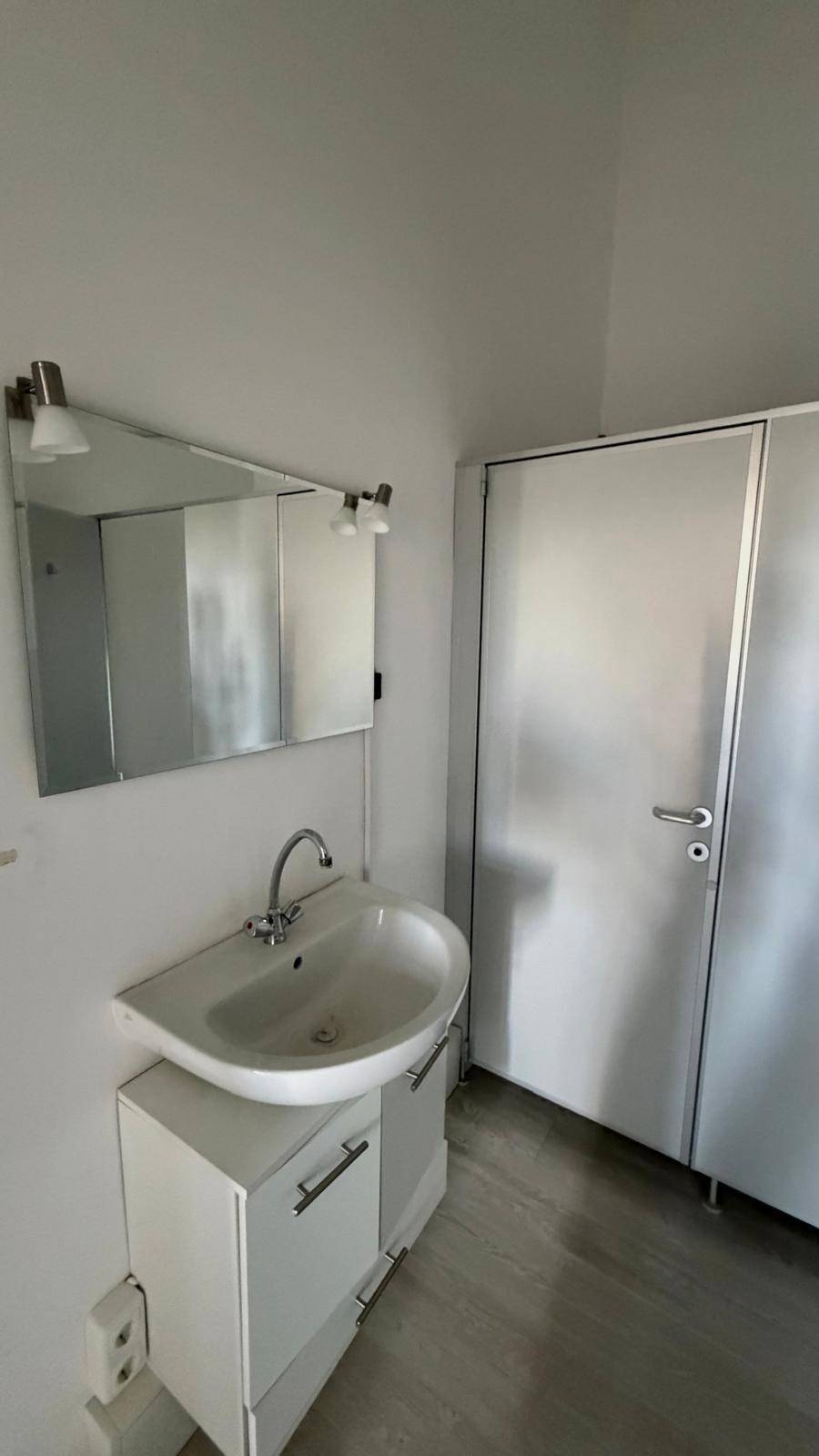 Modernes Badezimmer mit weißem Waschtischunterschrank, ovalem Waschbecken und Spiegelschrank.