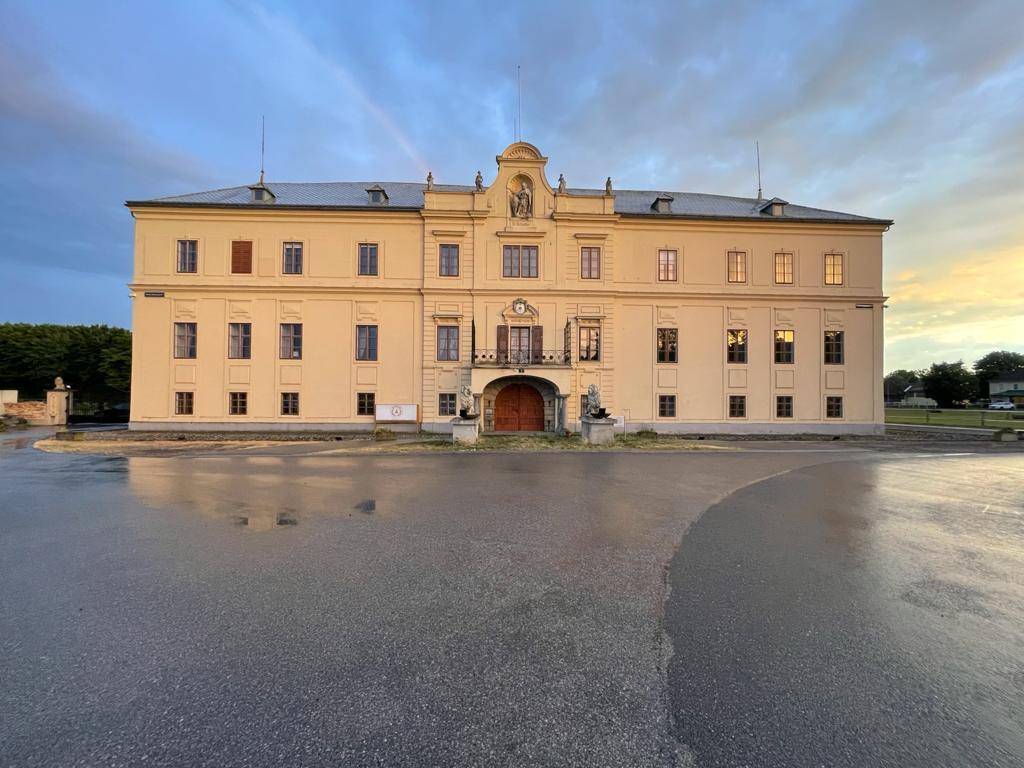 Historisches Gebäude mit klassischer Architektur und einem weitläufigen Vorplatz bei Sonnenuntergang.