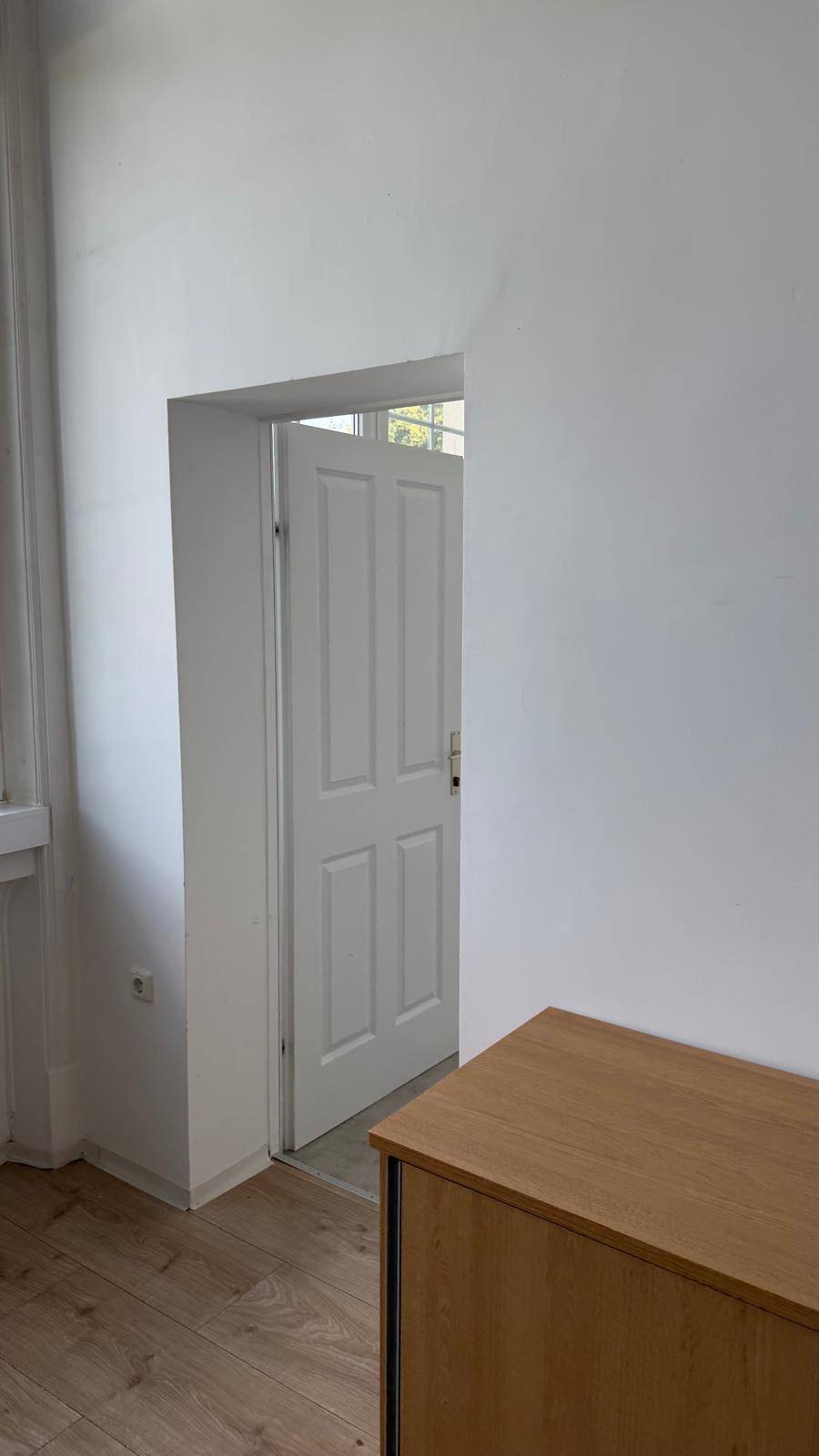 Türöffnung zu einem hellen Raum mit Laminatboden, von einem anderen Raum aus gesehen, schafft eine offene Verbindung.