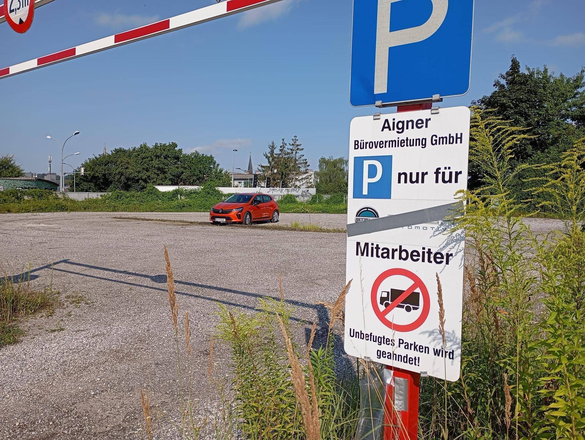 Schotterparkplatz mit einer Schranke und einem Schild, das auf Mitarbeiterparkplätze hinweist.