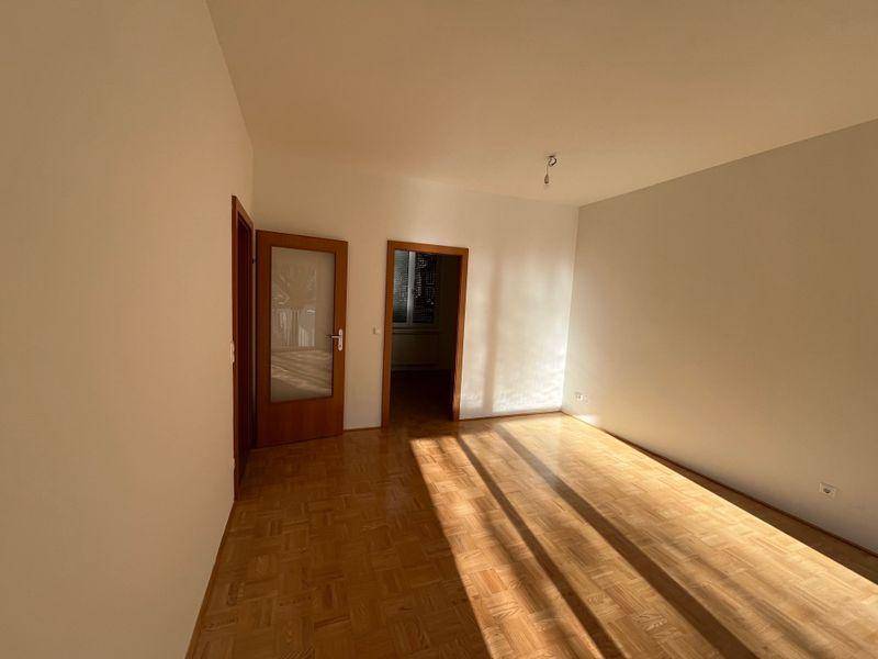 Helles, leeres Zimmer mit Parkettboden und Holztüren, bereit zur individuellen Gestaltung und Einrichtung.