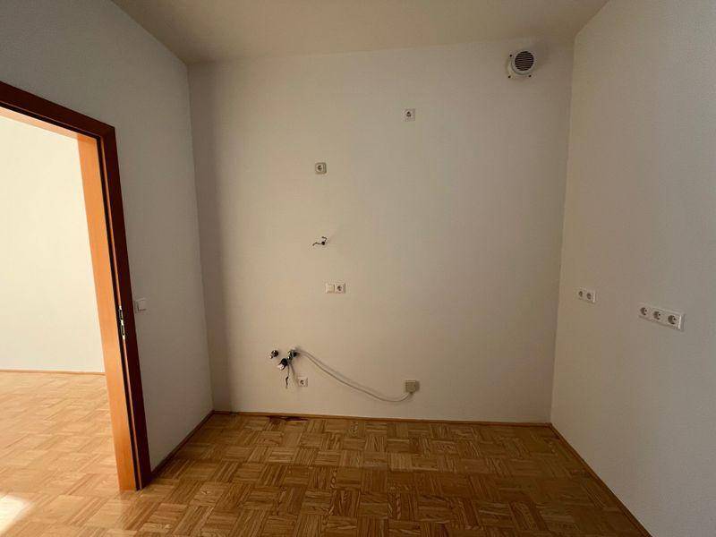 Leerer Küchenraum mit sichtbaren Anschlüssen für Spüle und Geräte, bereit für eine neue Einbauküche.