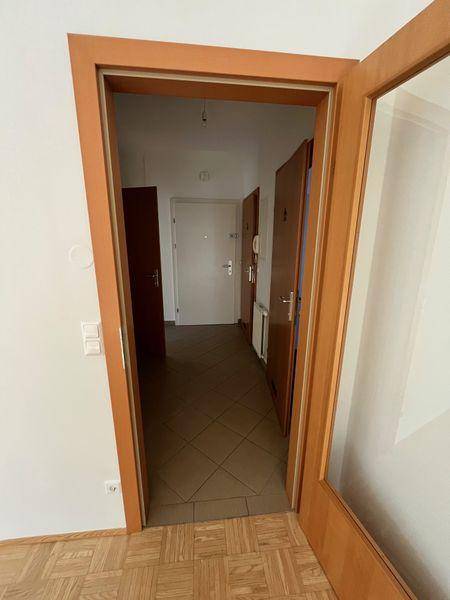 Langer Flur mit Fliesenboden und mehreren Holztüren, die zu den angrenzenden Räumen führen.