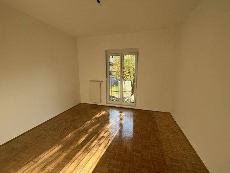 Helles Schlafzimmer mit Parkettboden und Zugang zu einem kleinen französischen Balkon, ideal für frische Luft.