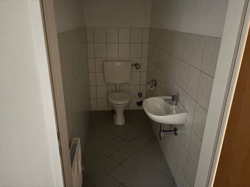 Kleines Gäste-WC mit Toilette und Waschbecken, vollständig gefliest und funktional.