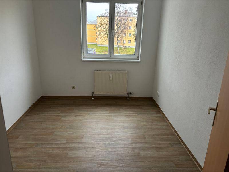 Geräumiges Zimmer mit Laminatboden und großem Fenster, ideal als Schlafzimmer oder Kinderzimmer.