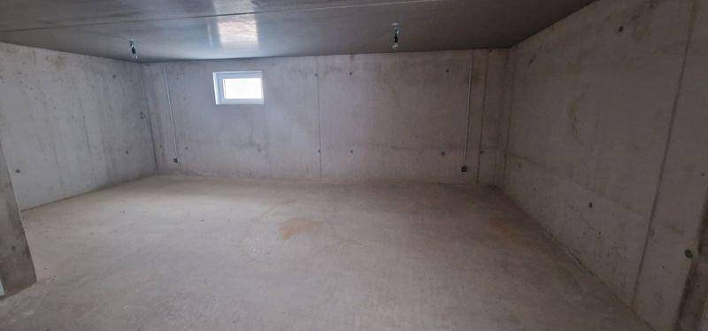 Unfertiger Kellerraum mit Betonwänden und kleinem Fenster, ideal als Abstellraum.