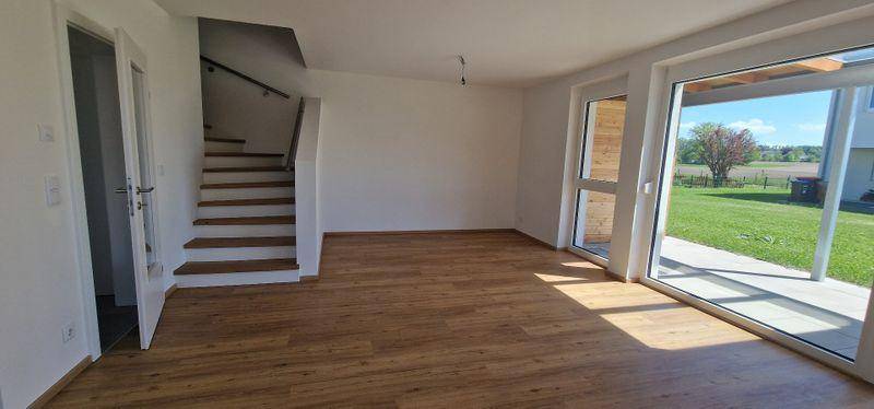 Heller Wohnbereich mit Treppenzugang zum Obergeschoss und direktem Gartenzugang.