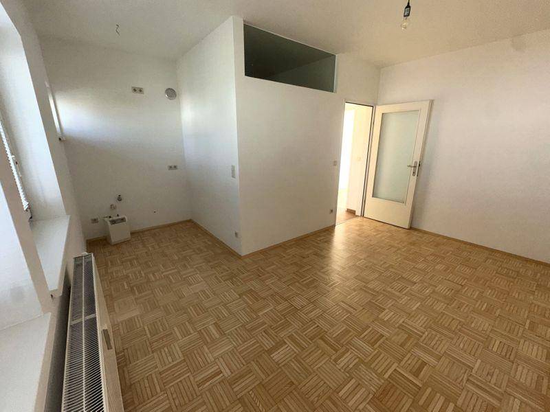 Helles Zimmer mit Parkettboden und Heizkörper unter dem Fenster.
