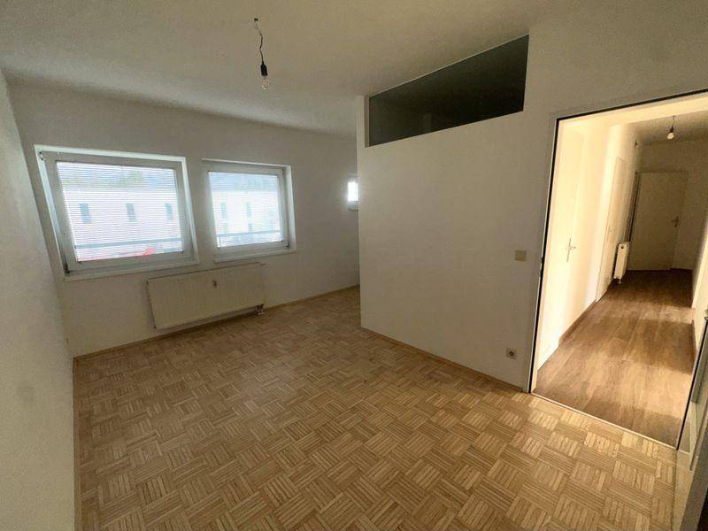 Geräumiges Zimmer mit Parkettboden und Blick in den Flur.