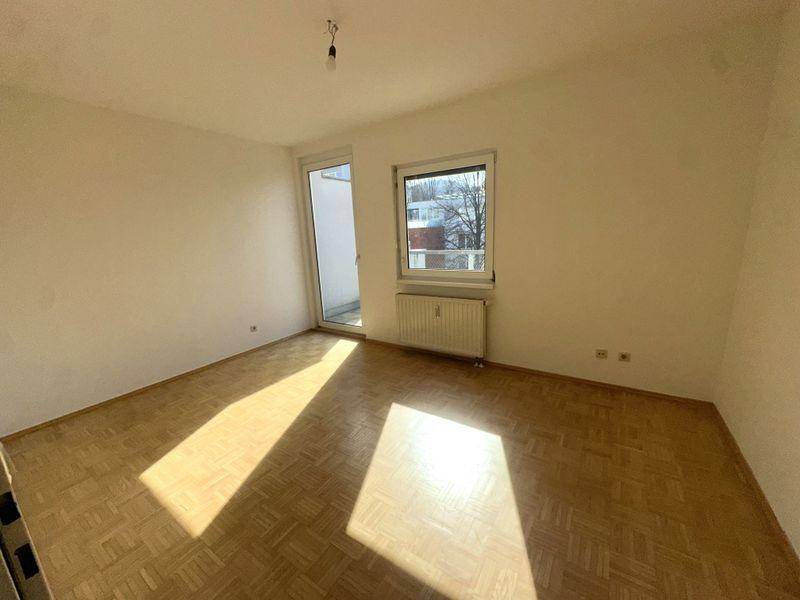 Lichtdurchflutetes Zimmer mit Parkettboden und Zugang zum Balkon.