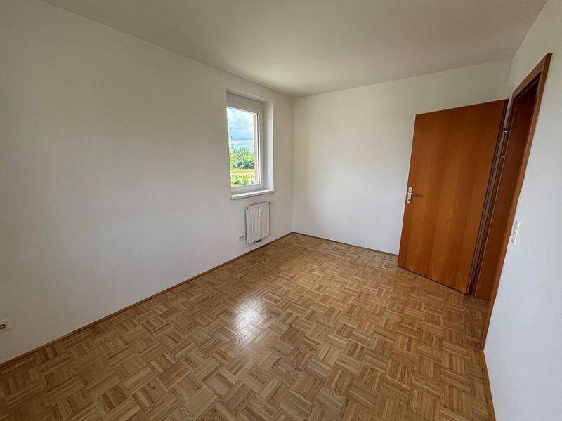 Ruhiges Zimmer mit Parkettboden und einem Fenster, bietet eine angenehme Atmosphäre.