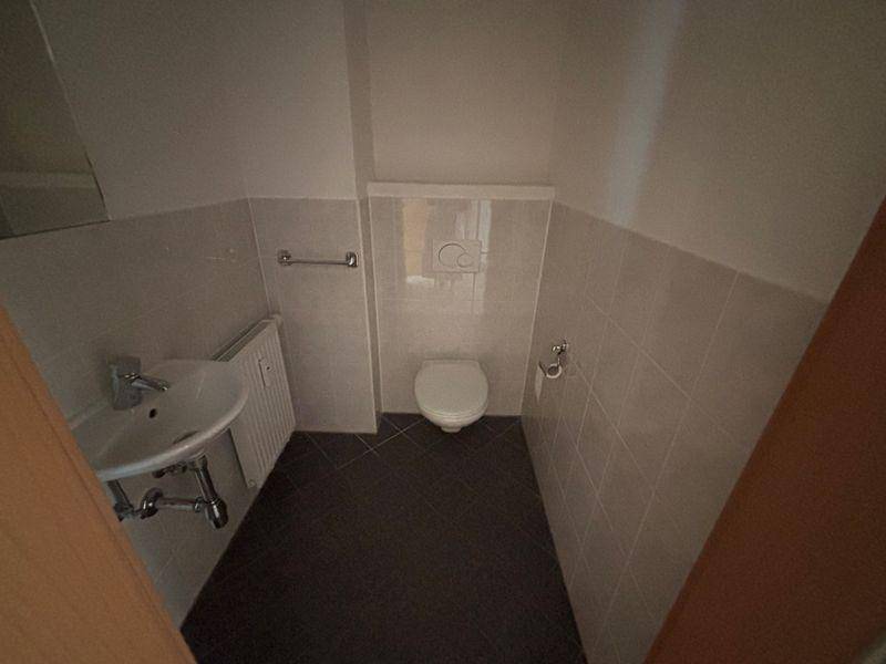Funktionales Gäste-WC mit modernen Fliesen und einem kompakten Waschbecken.