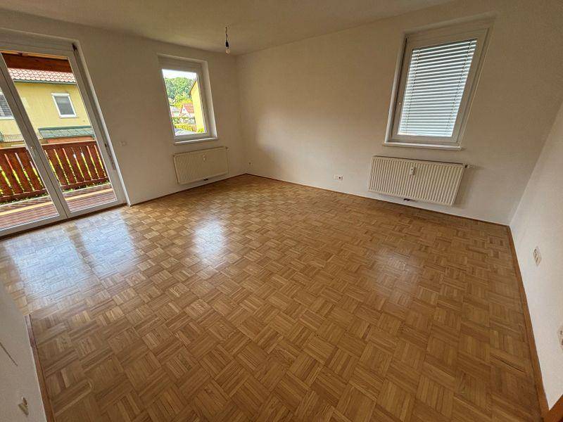 Geräumiges Wohnzimmer mit Parkettboden, Balkonzugang und mehreren Fenstern für viel Licht.