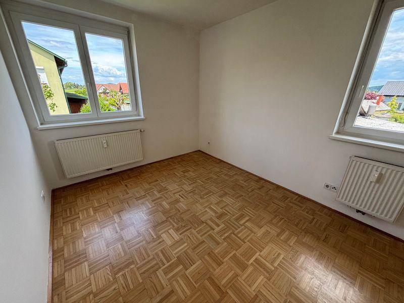 Helles Zimmer mit Parkettboden und zwei Fenstern, ideal als Schlaf- oder Arbeitszimmer.