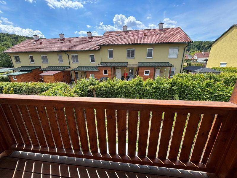Ausblick vom Balkon auf eine Reihe von Reihenhäusern mit gepflegten Gärten.