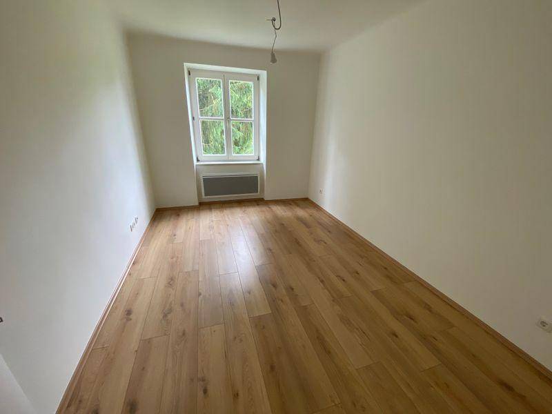 Geräumiges Zimmer mit Laminatboden und einem Fenster, das viel Tageslicht hereinlässt.