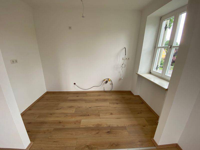 Leerer Küchenraum mit Anschlüssen für Spüle und Geräte, bereit für eine neue Einbauküche.