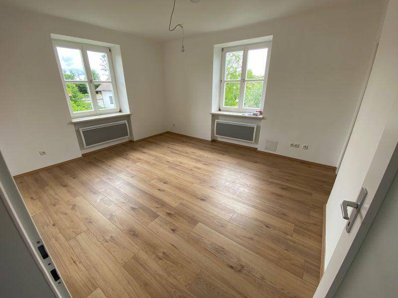 Geräumiges Zimmer mit zwei Fenstern, Laminatboden und Blick ins Grüne, ideal als Schlafzimmer.
