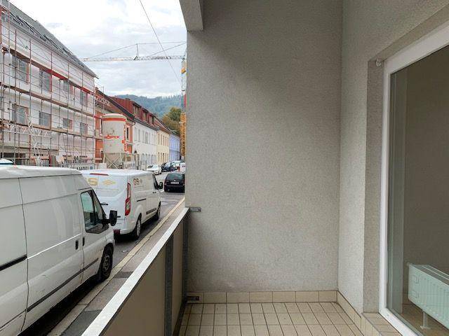 Blick vom Balkon auf die Straße mit parkenden Fahrzeugen und Baustellen in der Umgebung.