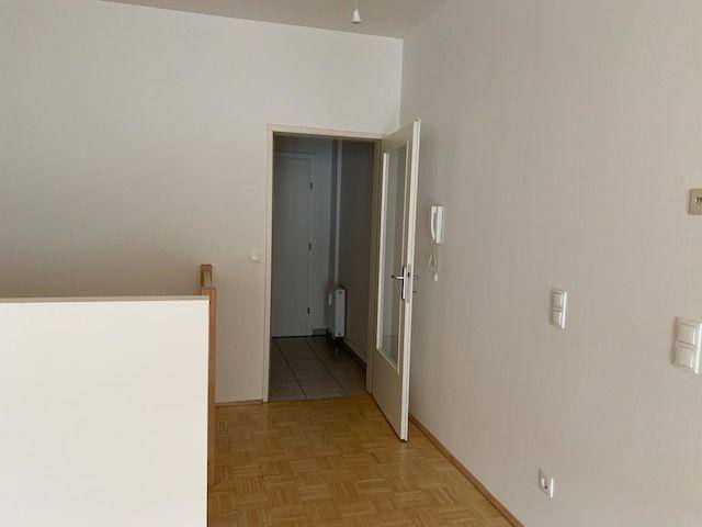 Heller Flur mit Parkettboden und offener Tür, die zu einem weiteren Raum führt.