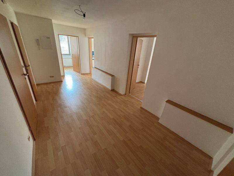 Heller Flur mit Laminatboden und Zugang zu mehreren Zimmern, frisch gestrichenen Wänden.