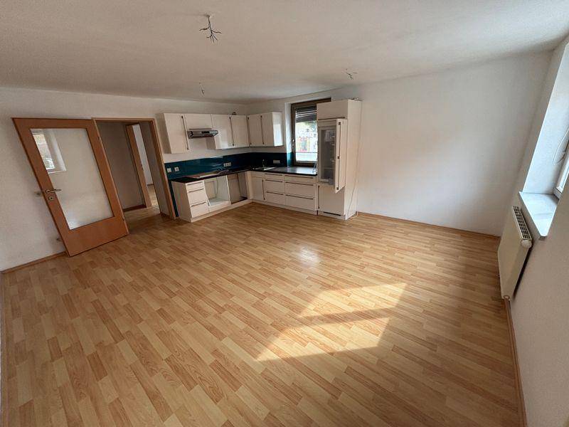 Großer offener Wohn-Essbereich mit Laminatboden und einer teilweise installierten Einbauküche.