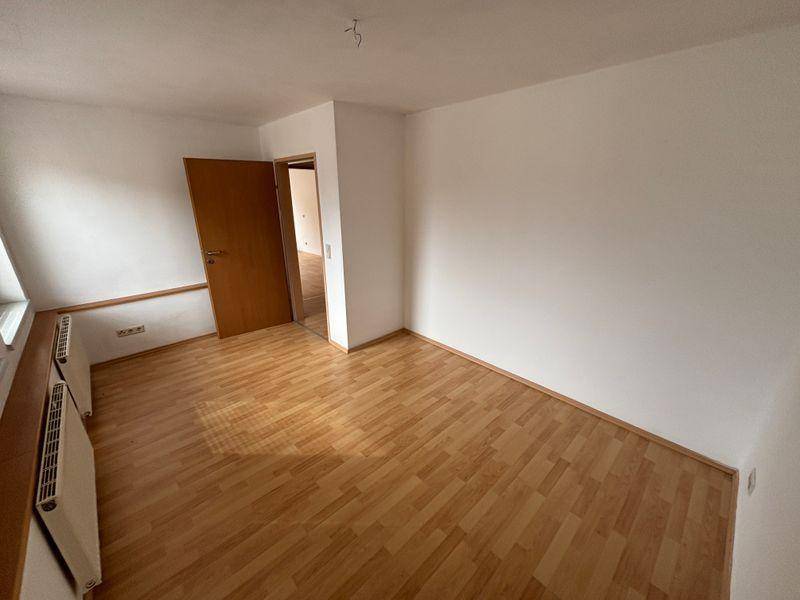 Geräumiges Zimmer mit Laminatboden und weiß gestrichenen Wänden, bereit zum Einzug.