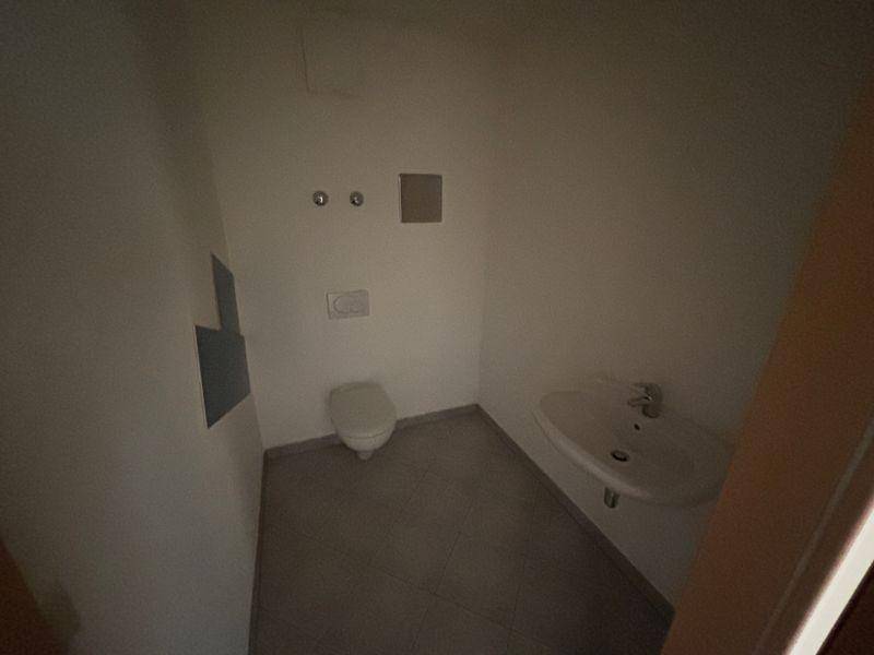 Kleines Gäste-WC mit Toilette, Waschbecken und Fliesenboden, funktional und sauber.