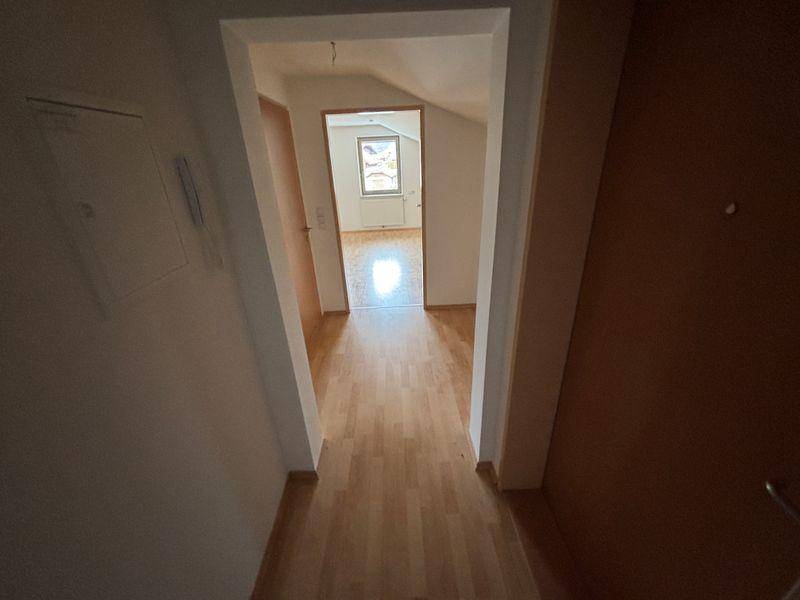 Heller Flur mit Laminatboden, der zu einem weiteren Zimmer mit Dachschräge und Fenster führt.
