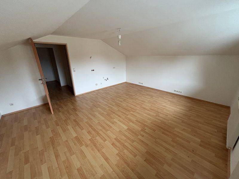 Geräumiges Zimmer im Dachgeschoss mit Laminatboden und weiß gestrichenen Wänden, unmöbliert und hell.