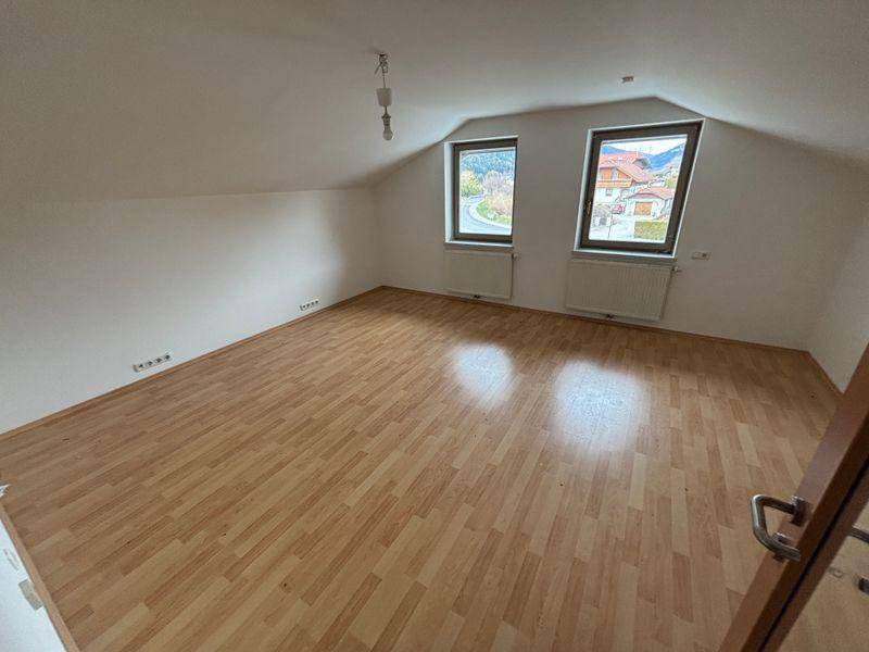 Geräumiges Dachgeschosszimmer mit Laminatboden und zwei Fenstern, die eine ländliche Aussicht bieten.
