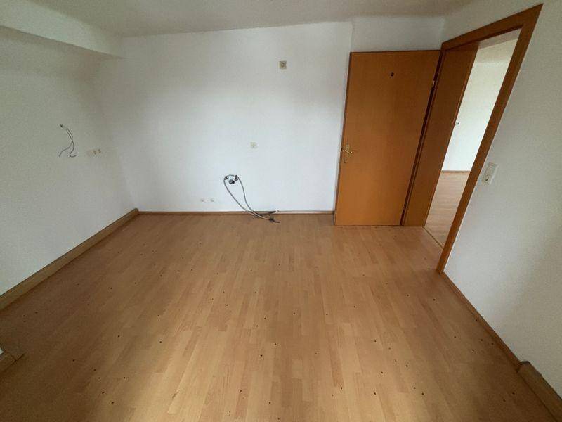 Leeres Schlafzimmer mit Laminatboden und einer Tür, bereit zur individuellen Gestaltung.