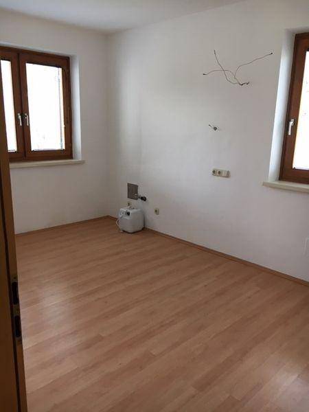 Geräumiges Zimmer mit Laminatboden und zwei Fenstern, ideal als Schlaf- oder Arbeitszimmer.