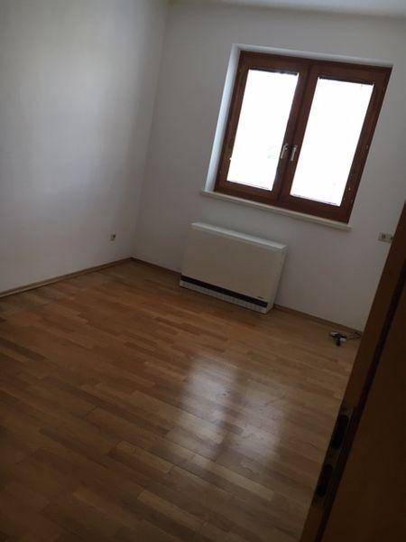 Helles Zimmer mit Laminatboden und einem Fenster, das viel Tageslicht hereinlässt.