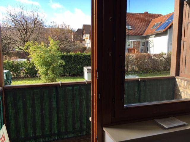 Mehrfamilienhaus mit mehreren Balkonen und Carport-Stellplätzen unter blauem Himmel.