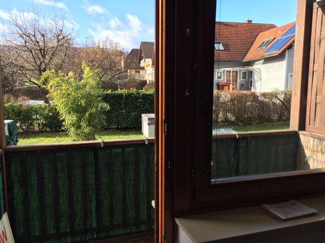 Mehrfamilienhaus mit mehreren Balkonen und Carport-Stellplätzen unter blauem Himmel.