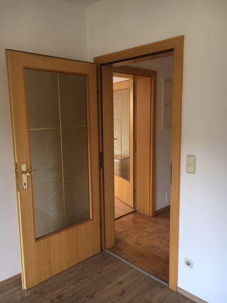 Blick durch eine Tür in einen Flur mit Laminatboden und weiteren Türen.